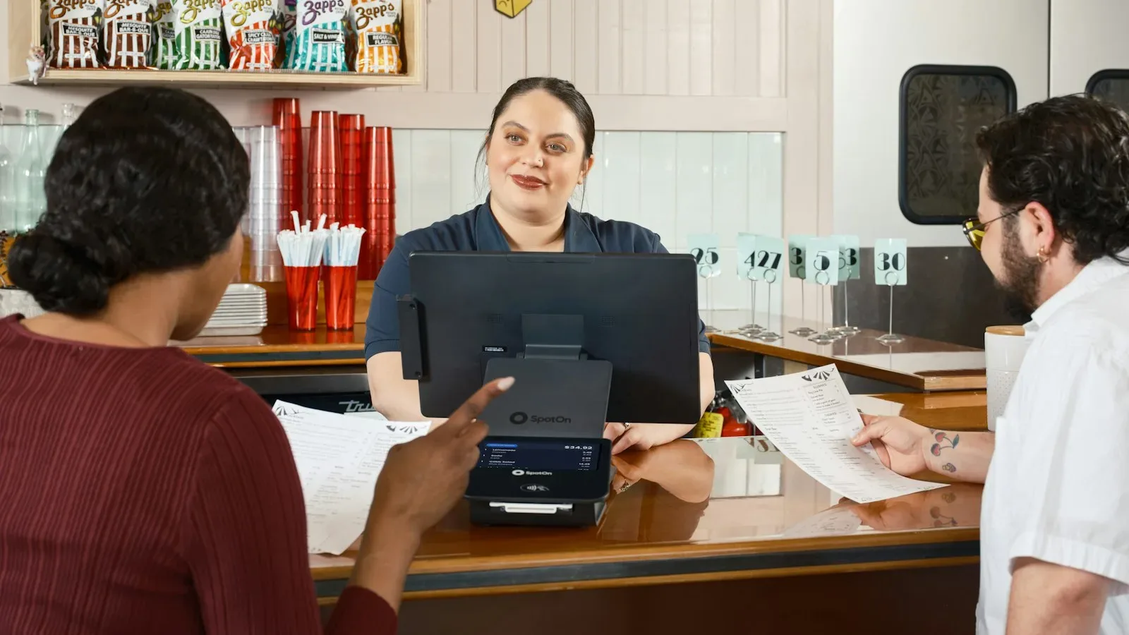 Small business owner welcoming first employee with payroll dashboard and legal forms visible