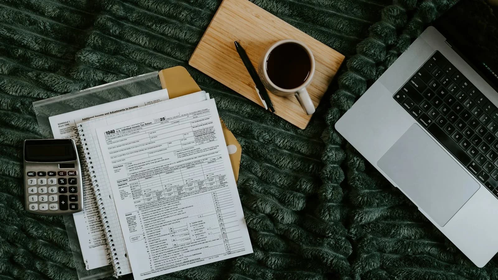 Small business owner reviewing cash‑flow forecast on laptop with printed spreadsheet and coffee mug